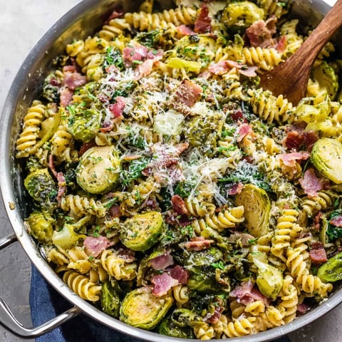 A bowl of pasta with bacon and brussels sprouts.