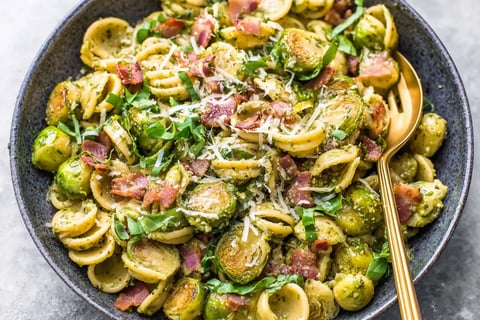 A bowl of pasta with bacon and Brussels sprouts.